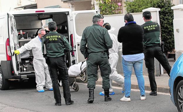 Efectivos de los servicios funerarios trasladan el cuerpo de uno de los hermanos ante la mirada de los guardias civiles./J. M. Rodríguez / AGM