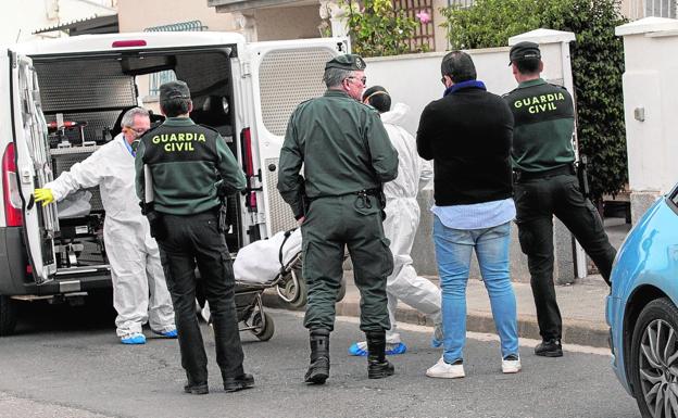 Efectivos de los servicios funerarios trasladan el cuerpo de uno de los hermanos ante la mirada de los guardias civiles./José María Rodríguez / AGM