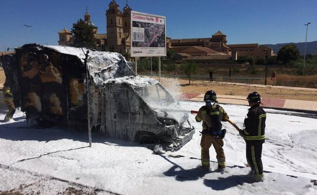 Dos agentes de bomberos apagan el incendio en un camión frigorífico.