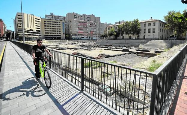 Un ciclista ayer circulando por la acera que rodea al yacimiento, donde se ha intervenido en la renovación del geotextil.