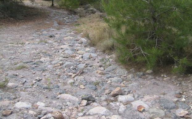 Detalles de la calzada romana de Portmán, con la señalización en su inicio, junto a la carretera de Atamaría, y la bahía al fondo