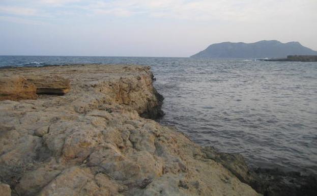 El puerto de época romana cortado a pico en una cala acantilada. Al fondo se adivina la silueta de Cabo Cope./