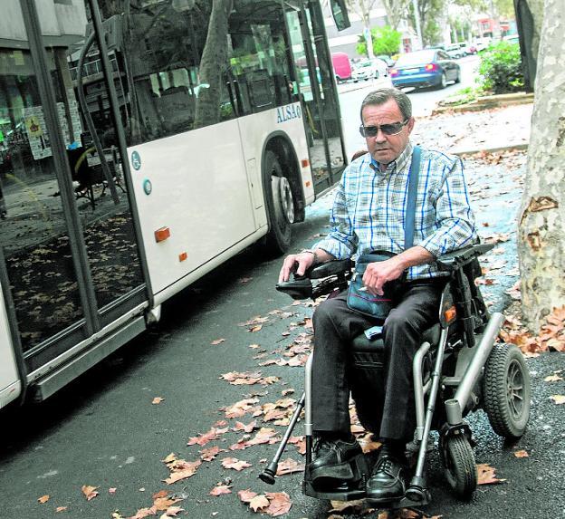 Juan Pedreño, que va en silla de ruedas, junto a un autobús en el Paseo Alfonso XIII./J. M. Rodríguez / AGM