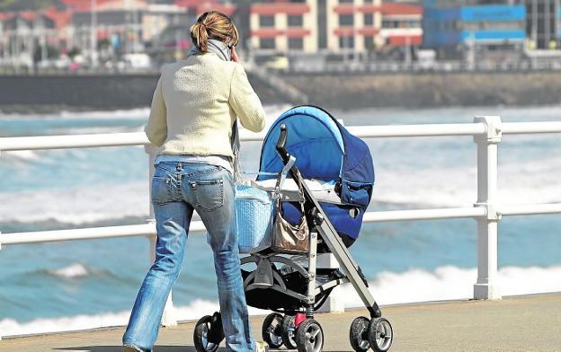 Una madre pasea a su bebé mientras habla por teléfono./M. A. Fernández