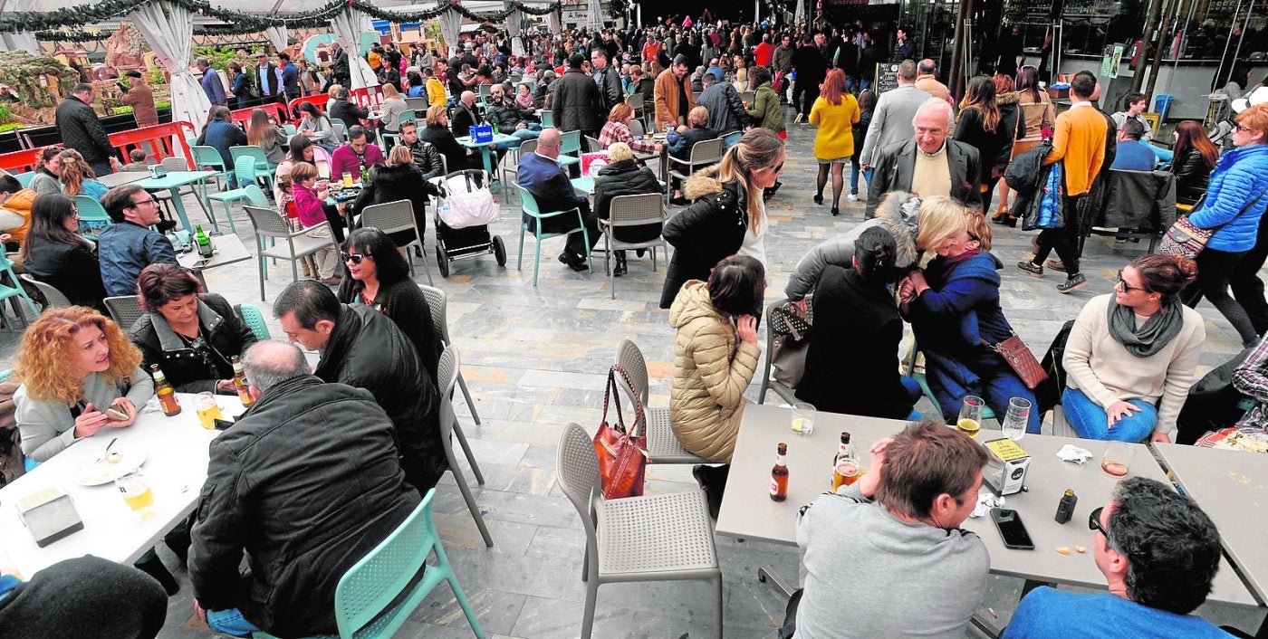La terraza de un bar de la Plaza San Francisco, repleta de clientes y al fondo, el escenario y el Belén Municipal./Antonio Gil / AGM