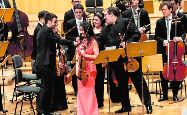 La violinista Lina Tur y el viola Joaquín Riquelme saludan a los músicos de la Orquesta de Jóvenes de la Región de Murcia y a su directora, Virginia Martínez, ayer, sobre el escenario del Auditorio regional Víctor Villegas./Juan Carlos Caval / AGM