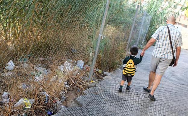 Un padre lleva a su hijo al colegio por un camino repleto de basura en Murcia en una imagen de archivo, /E. Botella/ AGM