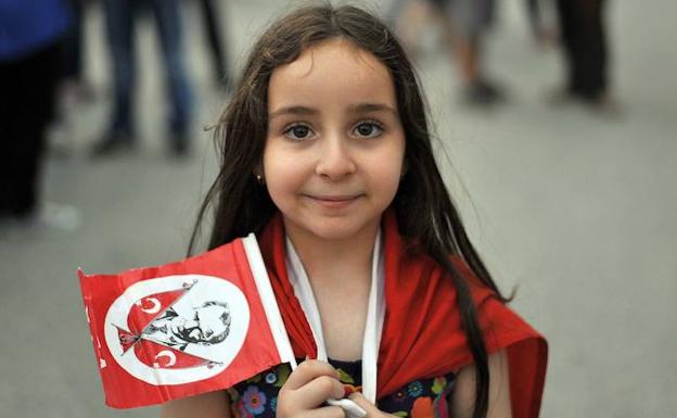 Una niña posa con una banderola adornada con la imagen de Mustafa Kemal Ataturk, fundador del estado moderno de Turquía. /OZAN KOSE (AFP)