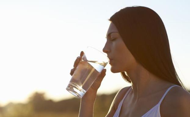Una mujer bebe agua./
