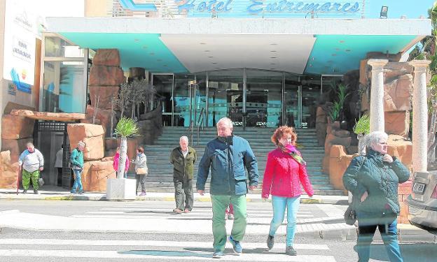 Unos turistas salen abrigados del hotel Entremares en La Manga del Mar Menor, ayer. / pedro martínez / agm