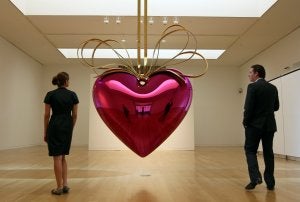 Dos empleados de Sotheby's contemplan la obra de Jeff Koons que fue subastada por dicha casa de pujas. / AFP/
