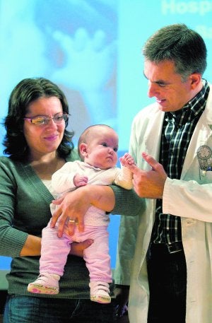 El doctor César García juega con la pequeña Esther Bota, de cuatro meses, en brazos de su madre. ::
MARTA PÉREZ/EFE/