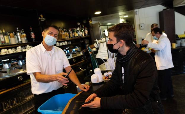 A waiter scans the QR code on a customer's vaccination certificate.