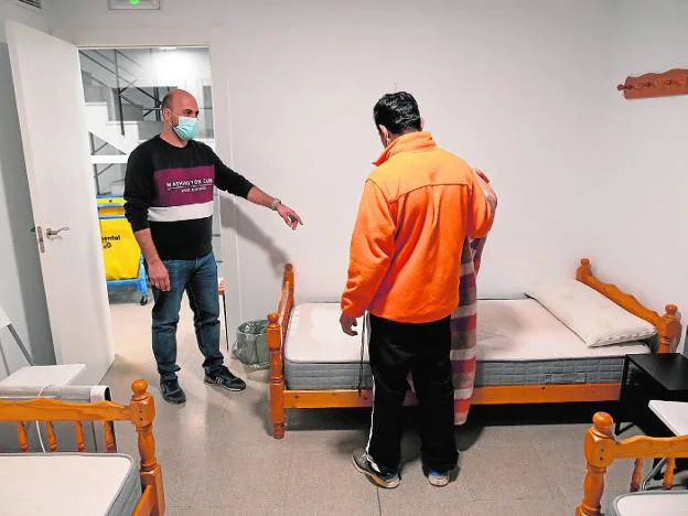 The Cáritas technician indicates to a user who has just arrived at the shelter the bed where he is going to sleep. 