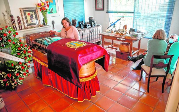 Encarna Moreno, her caregiver, before the coffin with the remains of Margarita Lozano in the main hall of the Casa Azul.  On the left, signatures in the book of condolences in the War. 