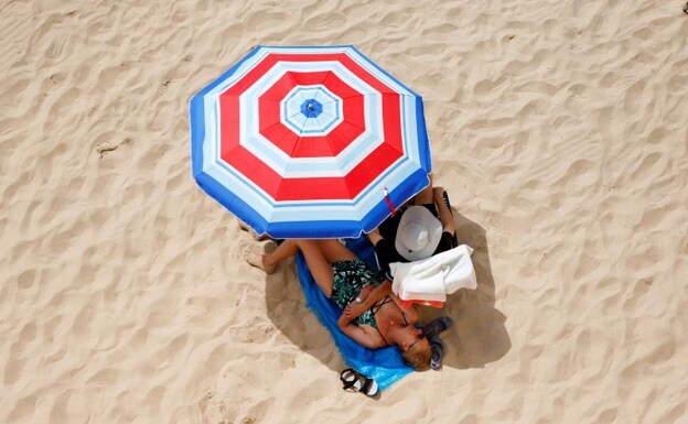 Two tourists sunbathe on the beaches of the Mediterranean.