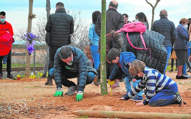 One of the families completes the planting of the tree that remembers their loved one in the Paseo del Arcoíris de Torre Pacheco. 