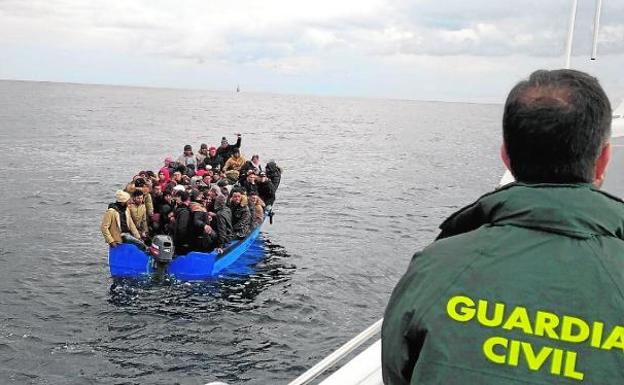 The occupants of a boat, full of immigrants, await the help of the Civil Guard. 