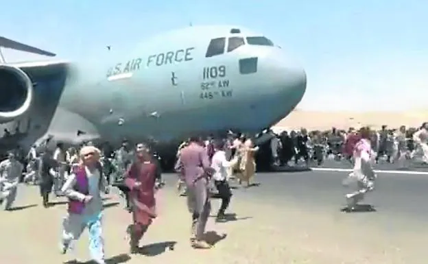 Hundreds of Afghans try to prevent the takeoff of a US military plane at Kabul airport, a year ago.