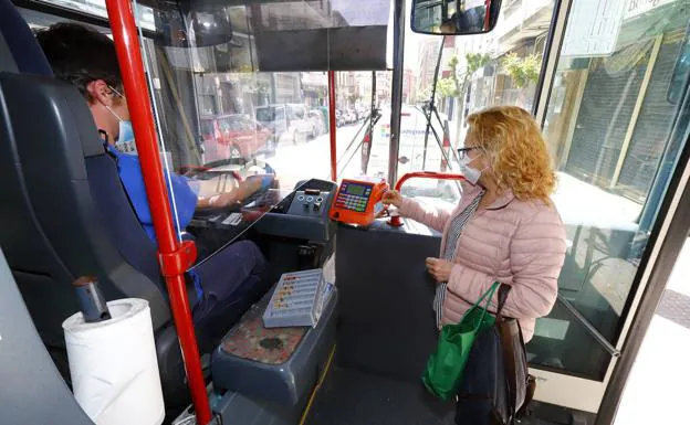 A passenger accesses a bus protected with a mask. 