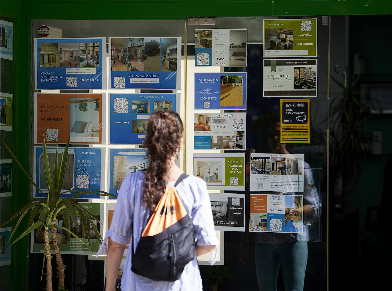 A young woman looks at the window of a real estate agency, in a file photo.