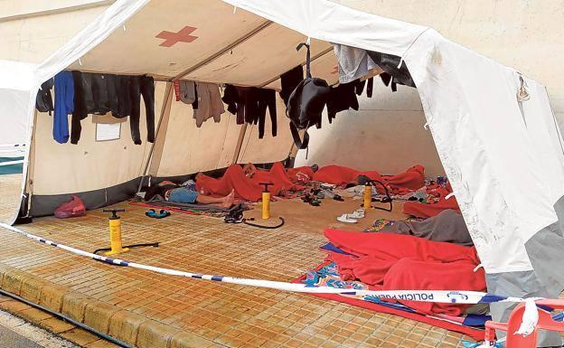 A group of immigrants rests in a Red Cross tent.