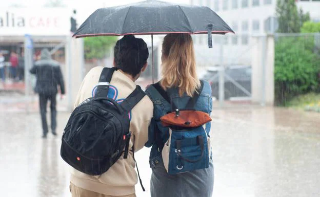 Two young people under an umbrella to protect themselves from the rain, in a file image. 