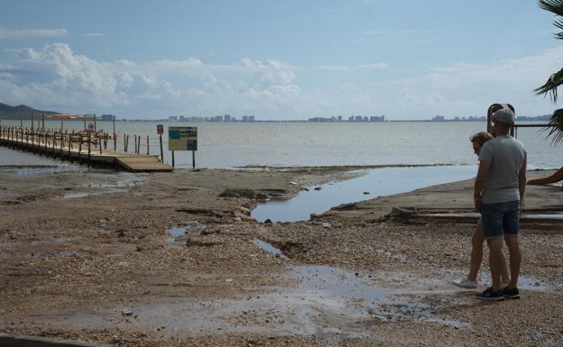 Two residents of Los Urrutias, yesterday, walking along the beach, where runoff from heavy rains is visible. 