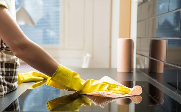 A woman cleans a countertop.