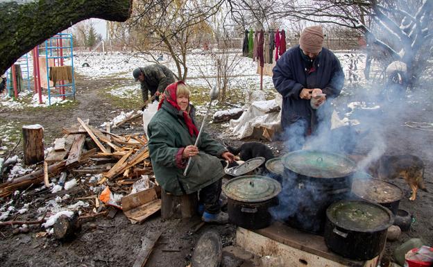 A woman cooks outdoors in front of her home in Cherkaski Tishki, in the Kharkiv region. 