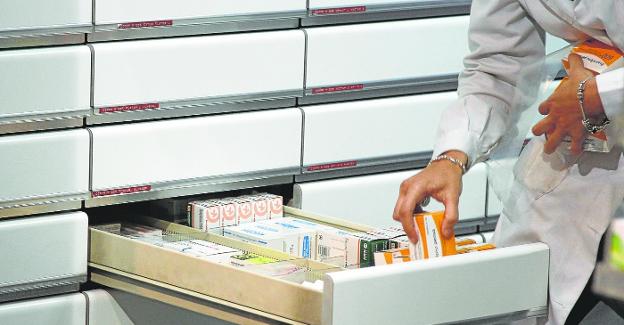 A worker places the medicines in the drawer of a pharmacy. 
