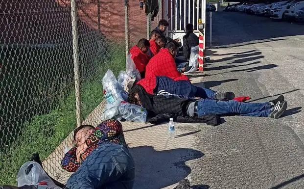 Several immigrants wait on the street after being intercepted as they got off the boat in which they were traveling. 