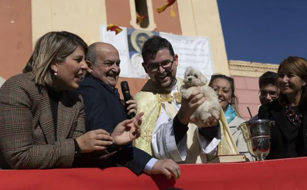 The parish priest holds a puppy during the celebration.