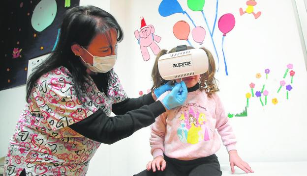 Cloe, 4, watches an explanatory video with virtual reality glasses while the nurse administers the vaccine, yesterday at the Antonio García de Molina de Segura health center. 