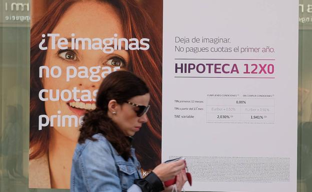 A woman walks past a billboard advertising a mortgage.